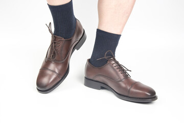 Male legs in socks and brown classic shoes on a white background