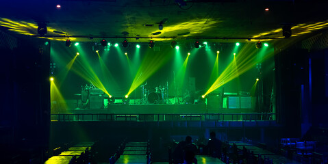 Fototapeta na wymiar Illuminated empty green concert stage with fog and rays of light in the nightclubs. Musical and dance concept. Lights beams on stage with musical instruments.