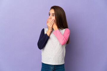 Little girl isolated on purple background covering mouth and looking to the side