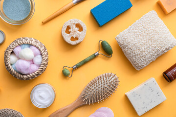 Natural cosmetic products on yellow background with copy space
Jade roller, cotton wool, vitamin c serum, solid shampoo, bath salts, loofah, hairbrush, face cream and pumice stone on yellow background