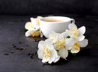 Fototapeta na wymiar Jasmine flowers and cup of healthy tea on a black background. Herbal medicine