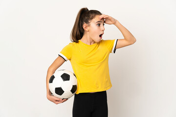 Little football player girl isolated on white background doing surprise gesture while looking to...
