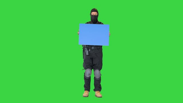 Riot policeman standing with a blank placard on a Green Screen, Chroma Key.