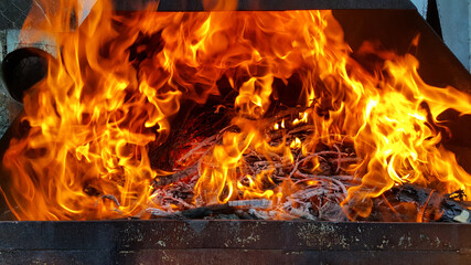 Empty flaming charcoal grill with an open fire, for cooking the product. The fiery background.