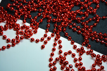 New Year and Christmas red beads for the New Year tree are randomly scattered on white and black fabric backgrounds.