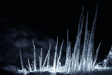sharp illuminated icicles in snow at dark night