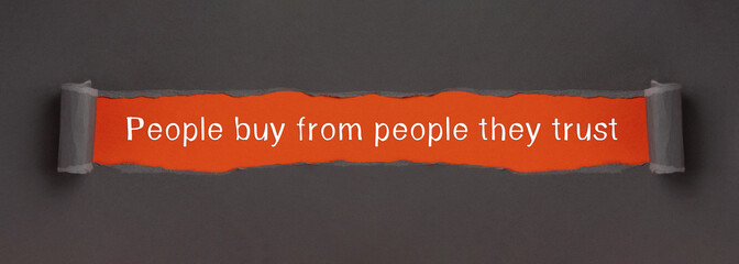 People buy from people they trust - appearing behind torn paper