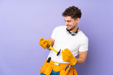 Young electrician man over isolated on purple background