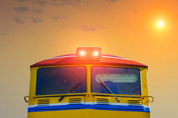Close up front view of train head or locomotive on sunset background.