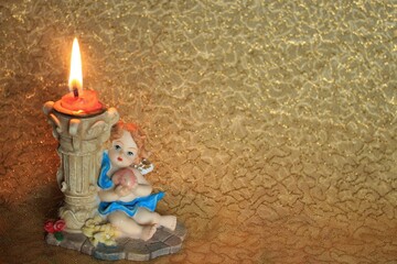 candle that marks the passing of time, Christmas period. Candle holder with angel - bright decoration on golden background - faith
