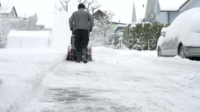 Man clearing snow from his driveway with a snow blower