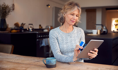 Mature Woman At Home Buying Products Or Services Online Using Digital Tablet And Credit Card
