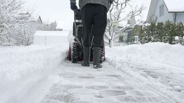 Cleaning snow from a driveway with snow blower machine