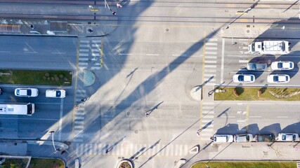 Aerial view of the city traffics at the center. Vehicles are moving on the road between buildings.