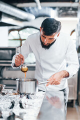 Cooks delicious soup. Chef in white uniform cooking food at kitchen. Busy day at work