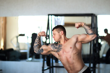 attractive young bodybuilder posing in a modern gym.