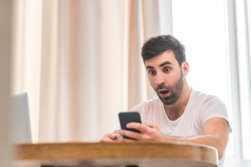 Photo of young man looking at his smartphone while text messaging isolated on white background.