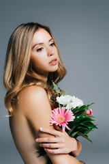 charming, topless woman posing with flowers isolated on grey