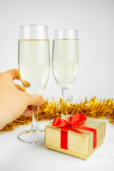 Two glasses with champagne and gold gift box on white background