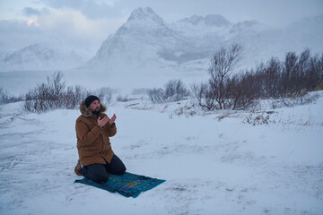 Fototapeta na wymiar Muslim traveler praying in cold snowy winter day