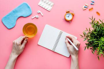 Female hand write in notebook - day plan before sleeping. Top view