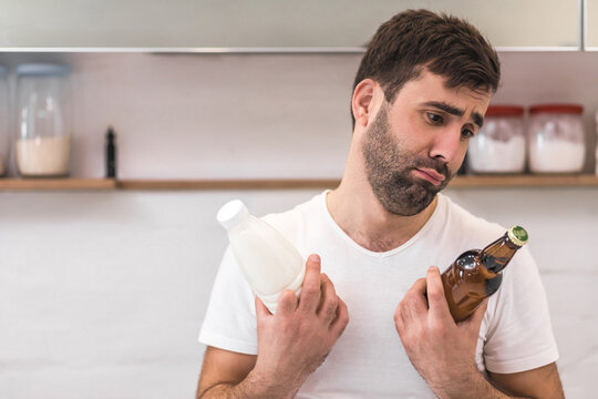 Photo of bearded man in the kitchen with a bottle of milk and beer.