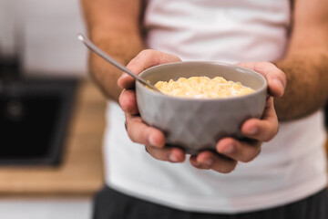 Cropped photo of man holding bowl of cereal with spoon.