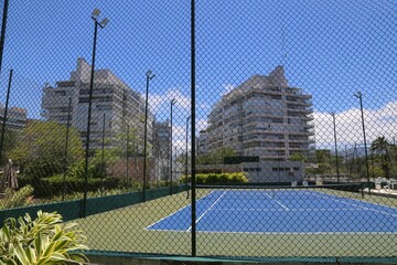 Modern buildings with tennis courts surrounded by wire mesh