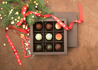 Various chocolate truffles box on a brown background with New Year's decoration