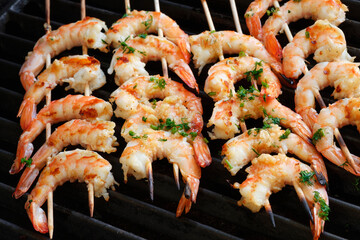 Grilled king prawns on wooden skewers.
