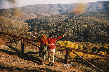 Rear view of happy couple in love spending free time in nature. Couple hugging and looking at beautiful view. Autumn time.