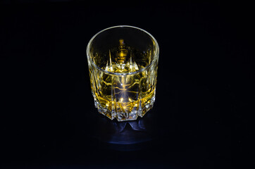 A glass of whiskey with ice on a black background. Copy the space.