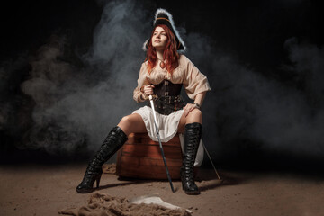 Obraz premium Young pirate female with long red hair. Woman is wearing a black corset bustier, tricorn hat , gun belt and armed with a pistol and sword.