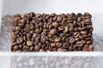 Perspective view on coffee beans in a transparent box on white background.