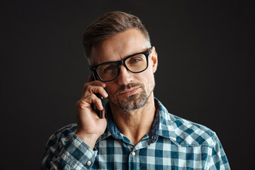 Serious grey-haired man talking by mobile phone