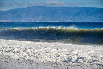 the sea stirred by the swirling wind forms large and noisy waves that crash on the shore with splashes and foam