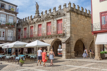 View at the medieval building S. Tiago, a iconic building on Plaza da Oliveira, tourist people...