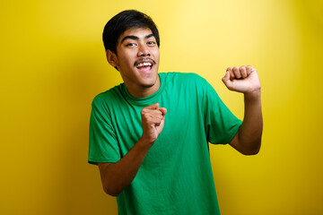 Asian man in green t-shirt smiling and dancing happily