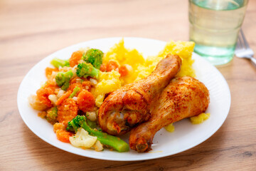 Baked chicken drumsticks with mashed potatoes and vegetables on the plate