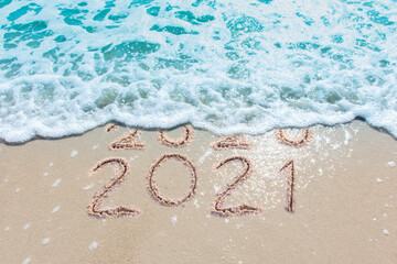 Message Year 2020 replaced by 2021 written on beach sand background. Good bye 2020 hello to 2021...