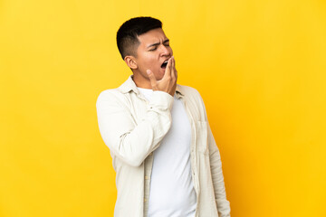 Young Ecuadorian man isolated on yellow background yawning and covering wide open mouth with hand