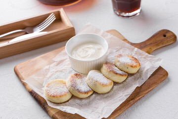 cottage cheese pancakes with sour cream sauce on wooden board on the table