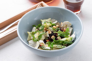 bowl of beet Salad with cream Cheese, hazelnut, Spring Greens and Herbs on white table