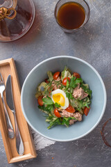 bowl of salad with tuna fish boiled egg and vegetable on white table at cafe