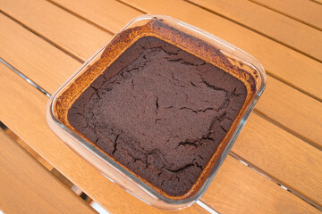 Homemade brownie in a glass dish. Just got out of the oven. Wooden table background.