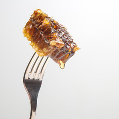 Drops of fresh honey drip from wax honey on a table fork. vitamin nutrition and bee product