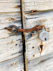 Old rusty padlock on weathered wood door with rusty nails.