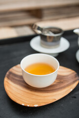 White porcelain tea cup. 
Fresh natural Qilan tea from Fujian province, a rolled oolong. Beautiful orange color. Vertical shot.