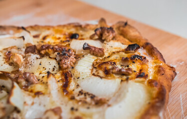 Delicious pizza with goat cheese, honey, nuts, onions and cream. Macro close up. 