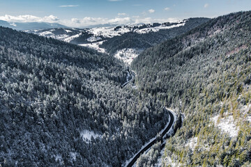road through the mountain pass. mountain winter road. Drone view of frozen winter forest and a curvy road.